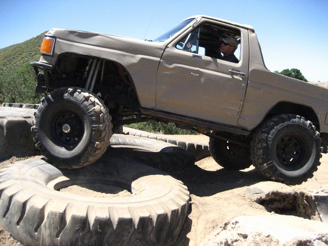 Tan off-road SUV with large tires navigating over large tire obstacles
