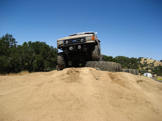 Tan Ford Bronco with large tires on a dirt mound