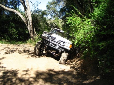 1989 Ford Bronco - This modified SUV is tackling a challenging off-road trail, its suspension and tire capabilities.