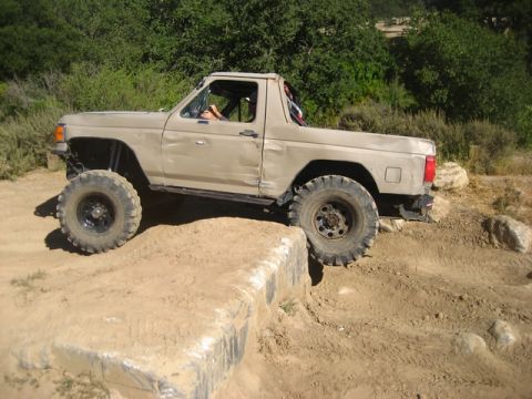 1989 Ford Bronco - This 1989 Ford Bronco is navigating a challenging off-road course with large tires.