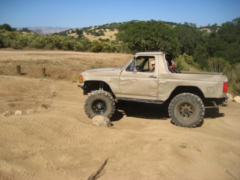 1989 Ford Bronco - This modified SUV navigates a rocky, off-road course under a clear blue sky.