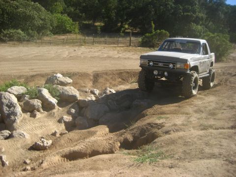 1989 Ford Bronco - This lifted Ford Bronco is tackling a challenging off-road course with large tires and a modified suspension.