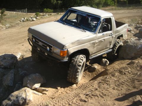 1989 Ford Bronco - Ford Bronco tackling rocks on an off-road trail, showing its suspension articulation.