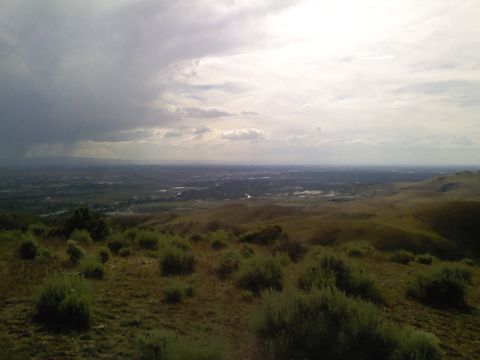 1981 Ford Bronco - A wide view of a valley under a stormy sky, with scrub brush in the foreground.