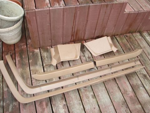 1989 Ford Bronco - Set of tan interior trim pieces for a vehicle, displayed on a weathered wooden deck.