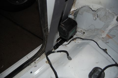 1994 Ford Bronco - Interior view of a vehicle's wiring harness and seatbelt anchor point, with visible signs of wear and tear.