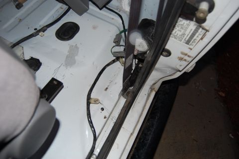 1994 Ford Bronco - Close-up of interior door wiring and seatbelt mechanism, with a visible sticker on the door frame.