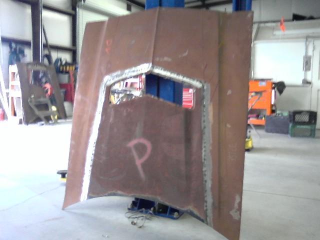 Rusty car hood with a large cutout, marked with a pink 'P'