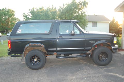 1994 Ford Bronco - This black Ford Bronco SUV shows significant rust around the wheel wells and running boards.