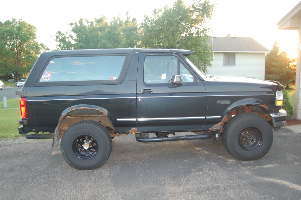 Black Ford Bronco SUV with rust on wheel wells and running boards, side view