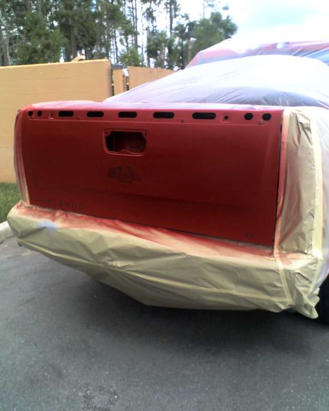 1993 Ford C-350 (Centurion Conversions) - The rear of a red pickup truck is prepped for painting, with masking materials covering the bumper and bed.