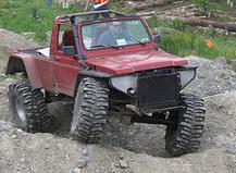 1987 Suzuki Samurai - This modified off-road vehicle appears to be participating in an event with other people in the background.