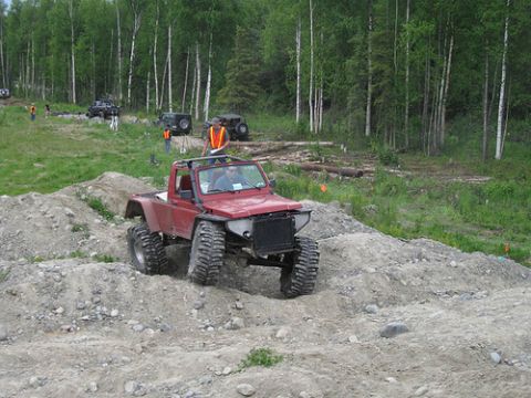 1987 Suzuki Samurai - A modified 1987 Suzuki Samurai navigates a challenging off-road course with other vehicles in the background.