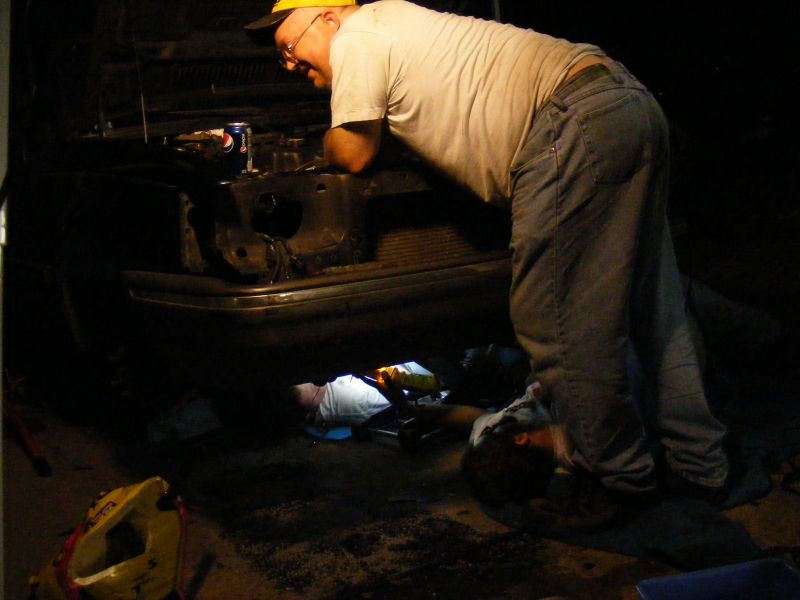 People working on a car engine at night