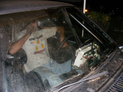 1989 Ford Escort - Interior view of a car with a person working on the exposed dashboard and a roll cage.