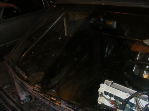 1989 Ford Escort - The interior of a dark vehicle is visible, a roll cage and exposed wiring, with a "Supermotors.net" watermark.