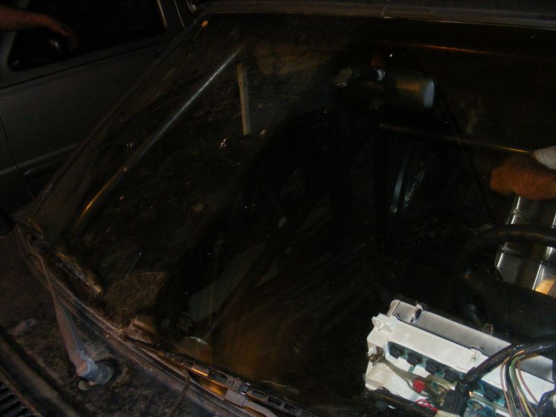 Interior view of a dark car with a roll cage and visible wiring