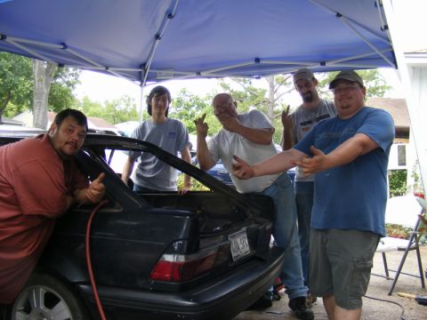 1989 Ford Escort - A group of men pose around the open trunk of a 1989 Ford Escort.