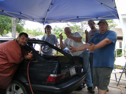 1989 Ford Escort - Men working on the trunk of a 1989 Ford Escort hatchback.
