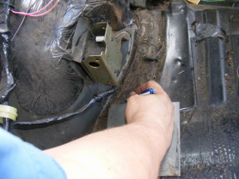1989 Ford Escort - Interior view of a car's floor pan, focusing on wiring and a mounting bracket.