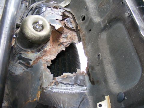 1989 Ford Escort - Severe rust damage is visible on the car's chassis, obscuring any identifying year or model details.
