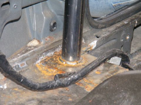 1989 Ford Escort - Significant rust is visible on the floor pan and around a structural support in this vehicle's interior.