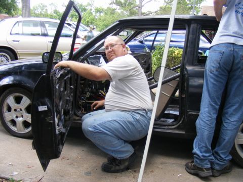 1989 Ford Escort - Two people are working on the interior of a car with its doors open.