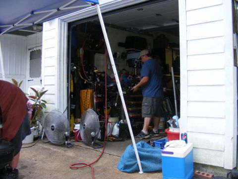 1989 Ford Escort - A cluttered garage interior is shown with various tools, fans, and a person working on equipment.