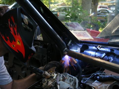 1989 Ford Escort - Welding a roll cage inside a car interior with sparks flying.