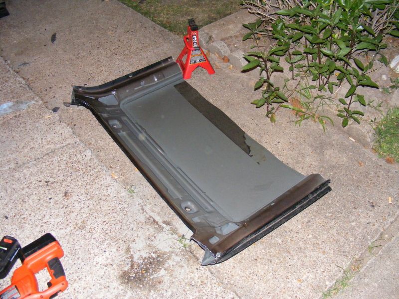 Car door panel lying on concrete with a red jack stand behind it