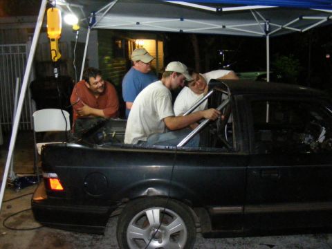 1989 Ford Escort - People are gathered around the interior of a car, appearing to work on modifications or repairs.