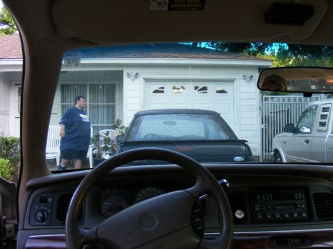 1989 Ford Escort - View from inside a car shows a garage scene with two vehicles and a person standing outside.