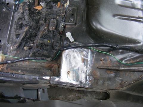 1989 Ford Escort - The interior floor pan shows evidence of rust repair with a welded patch and exposed wiring.