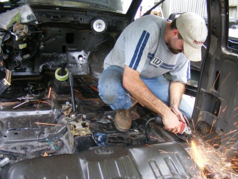 1989 Ford Escort - A person uses an angle grinder to work on the interior of a vehicle, creating a shower of sparks.