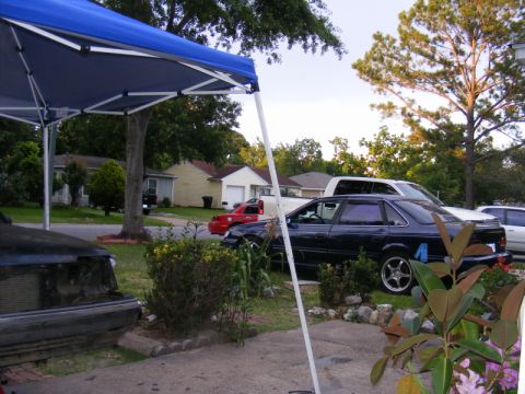 1989 Ford Escort - Several vehicles are parked in a residential driveway under a blue canopy.