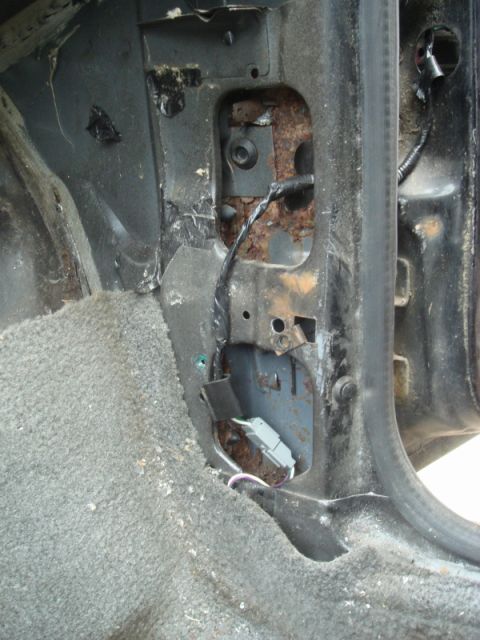 1989 Ford Escort - Close-up view of the interior door jamb area, showing significant rust and exposed wiring.