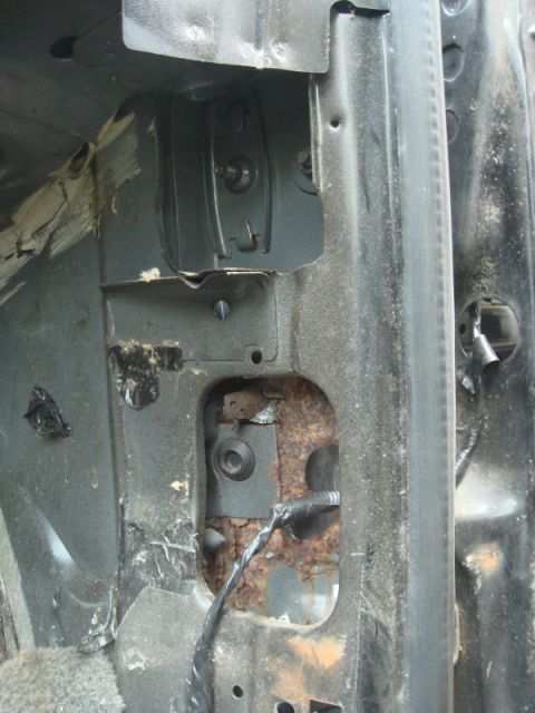 1989 Ford Escort - Close-up view of rusted metal and wiring, likely from a vehicle's interior structure.
