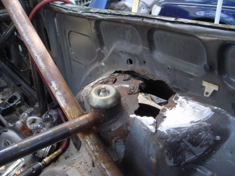 1989 Ford Escort - Severe rust damage is visible on the engine bay strut tower, with a roll cage bar obscuring part of the view.