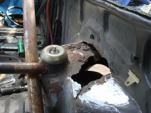1989 Ford Escort - Close-up of a heavily rusted car chassis section with a roll cage installed.