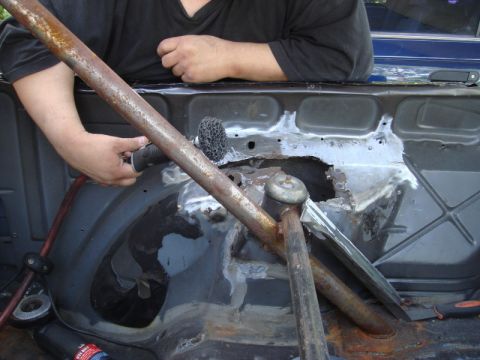 1989 Ford Escort - Rust damage is being addressed in the rear interior of a vehicle, revealing significant corrosion.