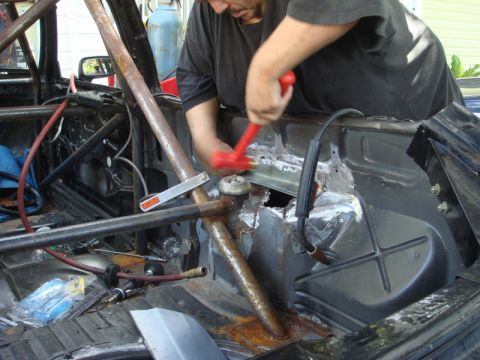 1989 Ford Escort - A person works on the interior of a car, which has been fitted with a roll cage.