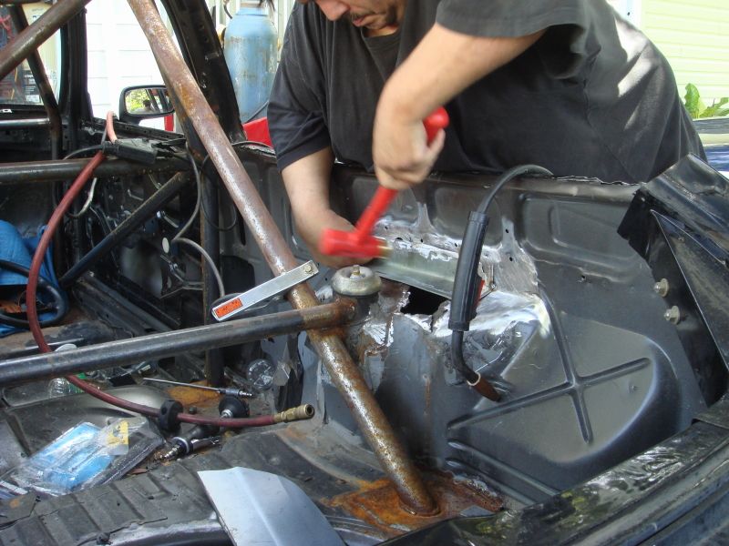 Interior of a car with roll cage, being worked on with a hammer