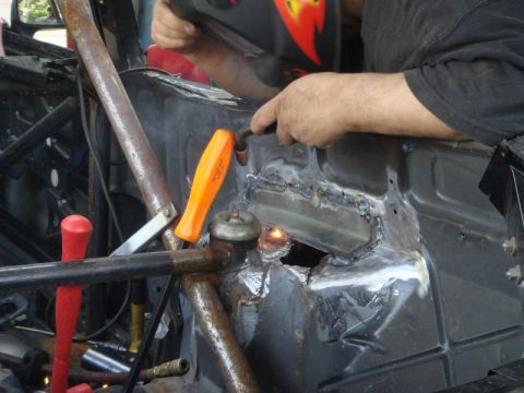 1989 Ford Escort - A person is welding a section of a car's interior bodywork, with various tools visible.