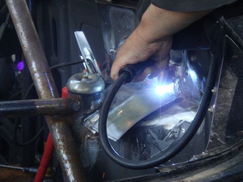 1989 Ford Escort - Welding is performed on a vehicle's engine bay, with the Supermotors logo visible in the lower right corner.
