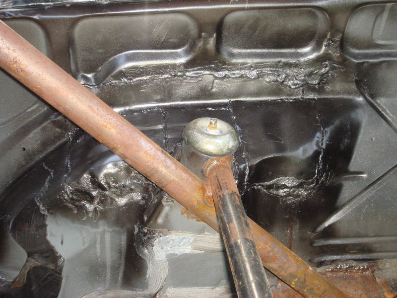 Car chassis interior with rusty roll cage and black painted floor panels