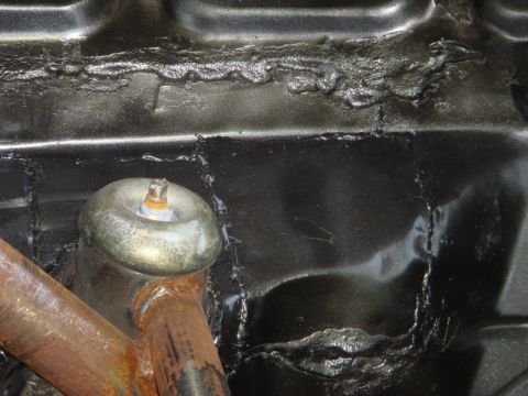 1989 Ford Escort - Detail of a vehicle's undercarriage showing a suspension component and sealant.
