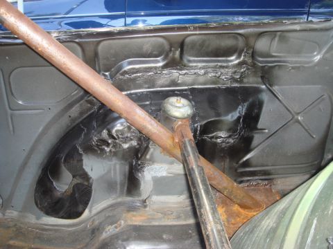 1989 Ford Escort - The interior of a car shows a roll cage installed in the rear wheel well area.