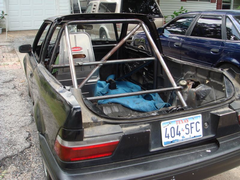 Car with roll cage and racing seat, rear view. Blue tarp in bed. Texas license plate 404 SFC
