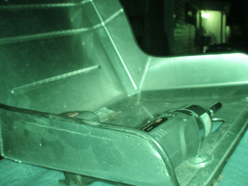 Close-up of a metallic car part with a rotary tool resting on it