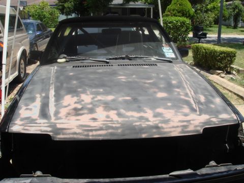 1989 Ford Escort - A car's hood is prepped for paint, with a glimpse of another vehicle in the background.